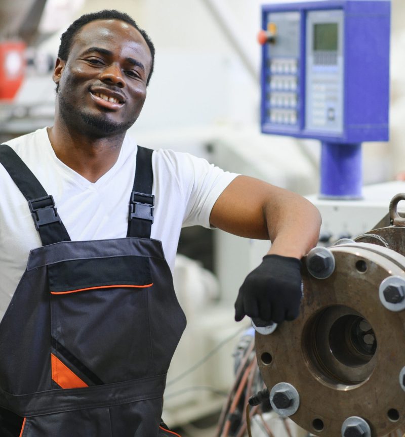Portrait of industrial engineer. Smiling factory worker standing in factory production line.
